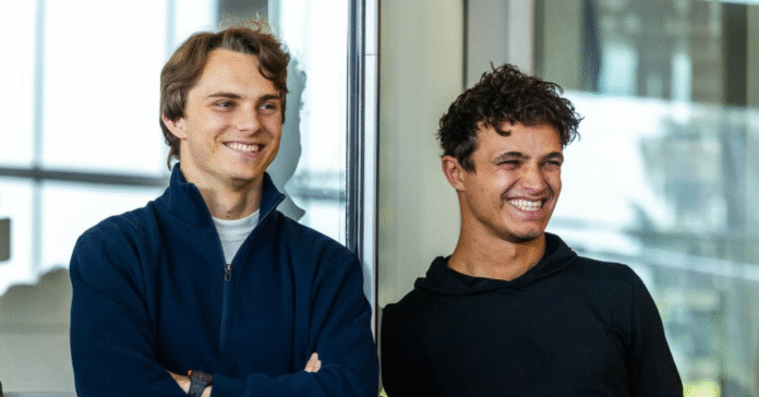 Oscar Piastri and Lando Norris smile as they look off to the side.